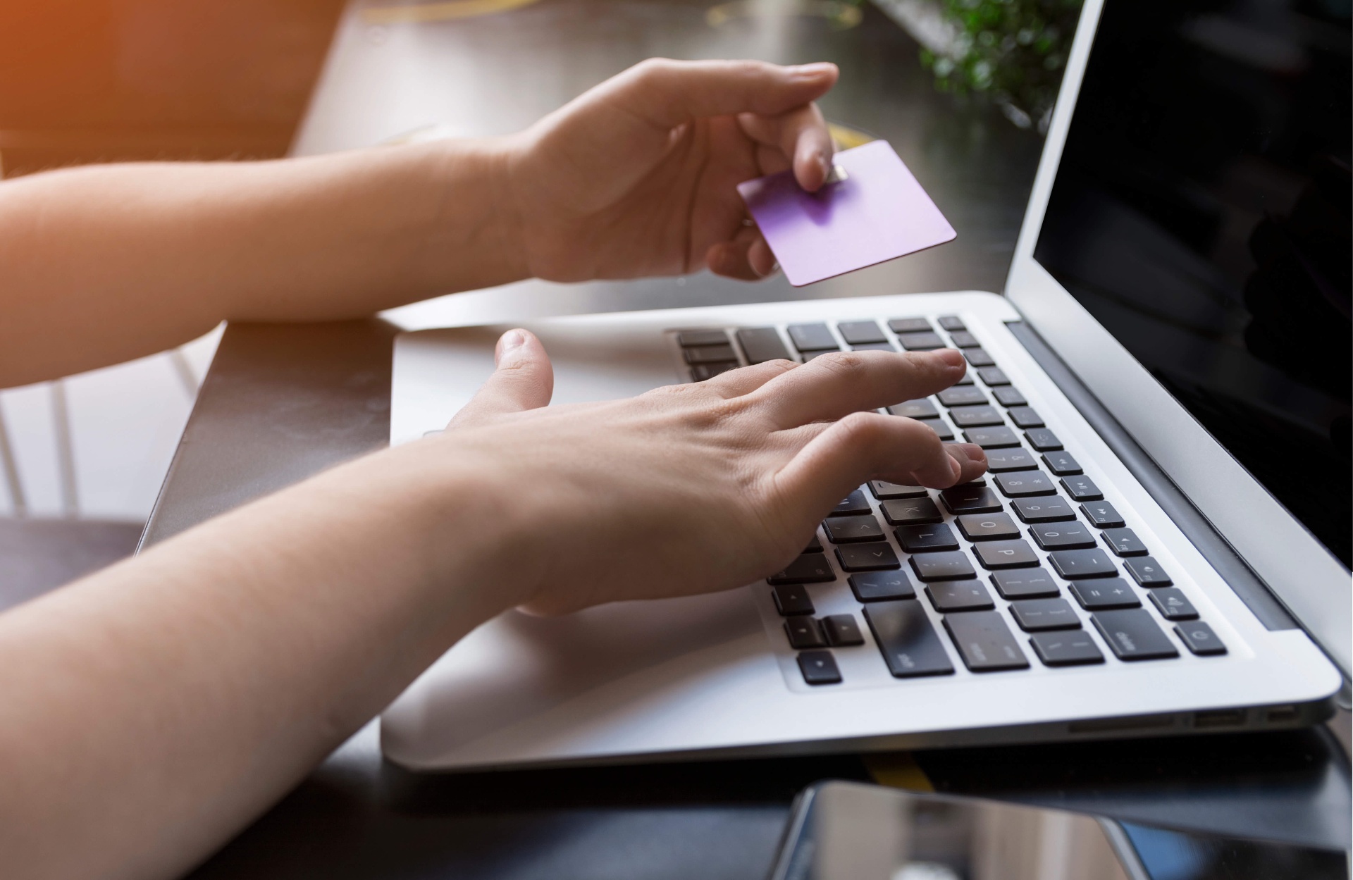 Mãos digitando no notebook com cartão de crédito